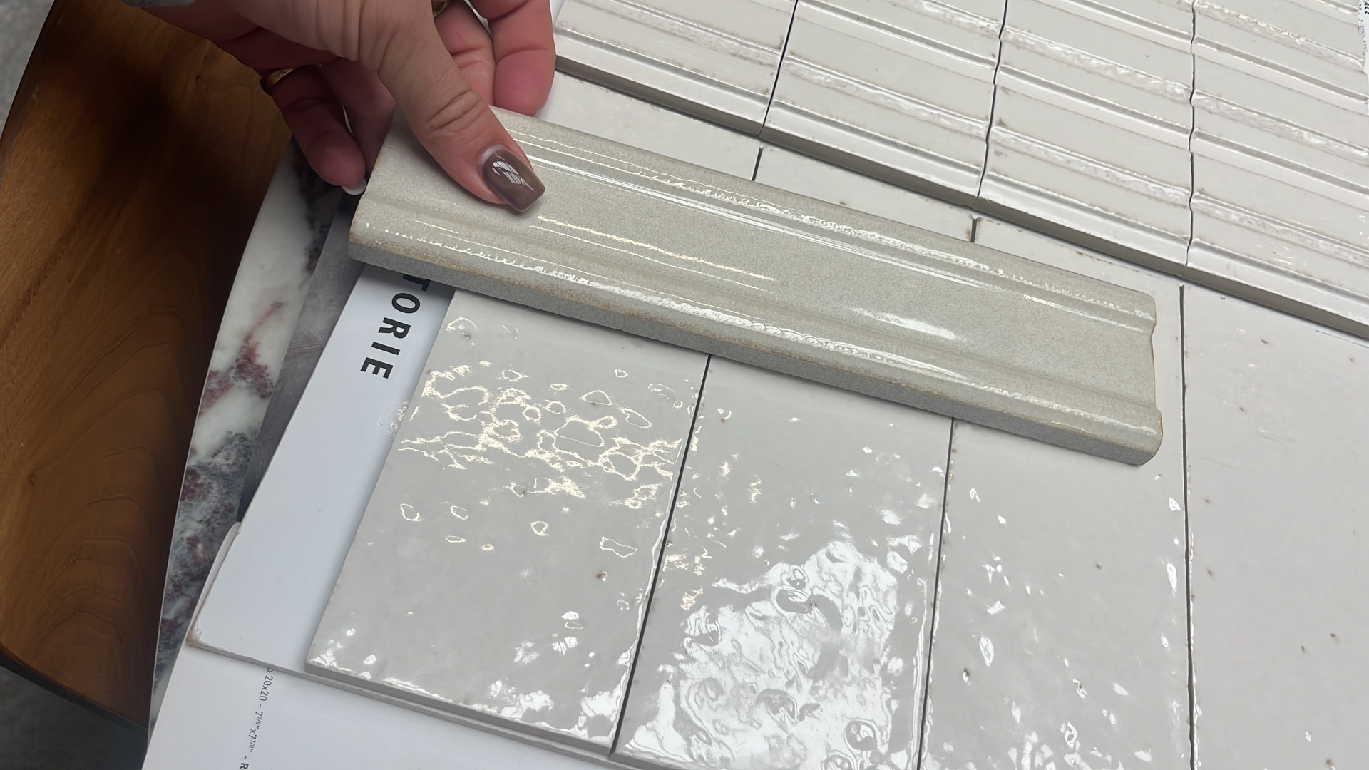 Handmade glazed wall tiles and moulded trim held against fluted tile samples