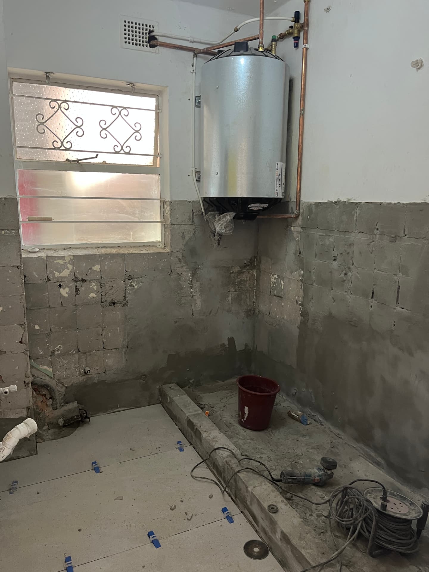 Stripped bathroom corner with geyser and new plumbing set out