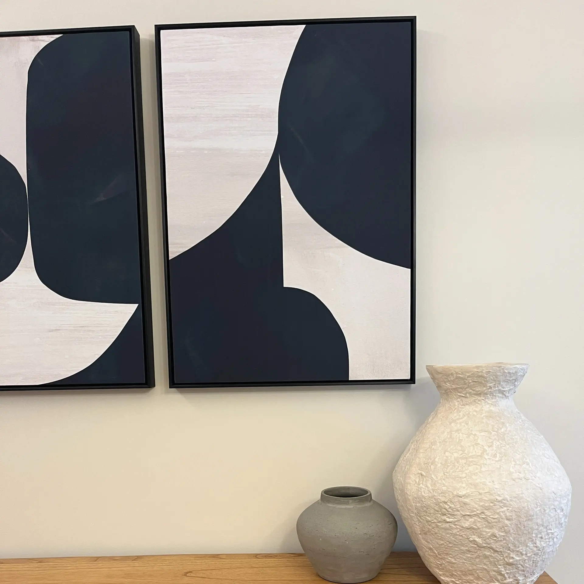 Graphic navy artwork above a console with textured ceramic vases