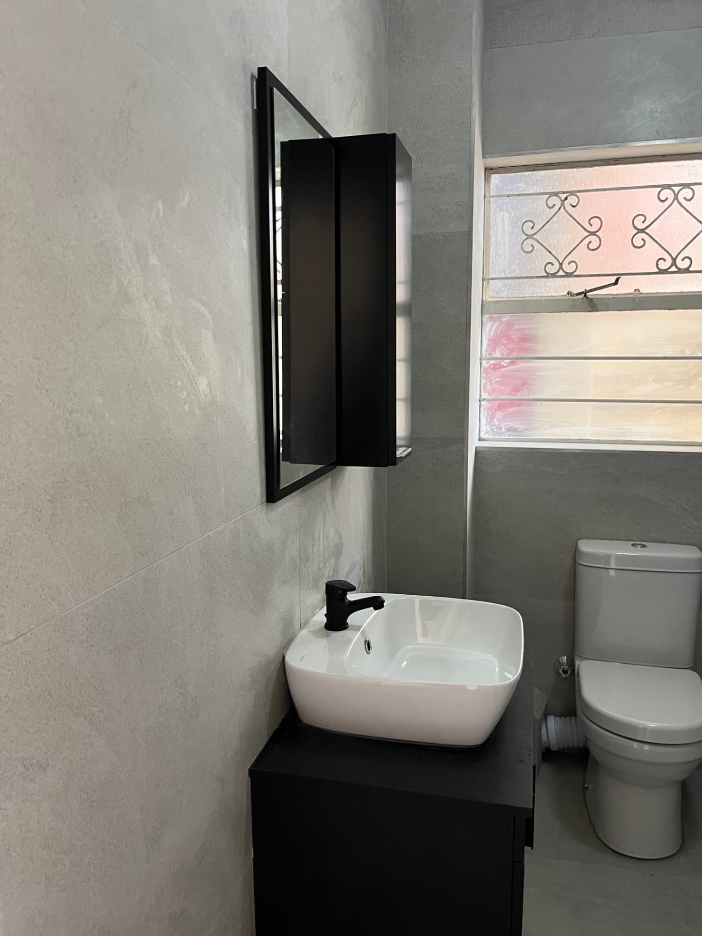 After: finished bathroom with black-framed mirror cabinet and stone-look wall tiles