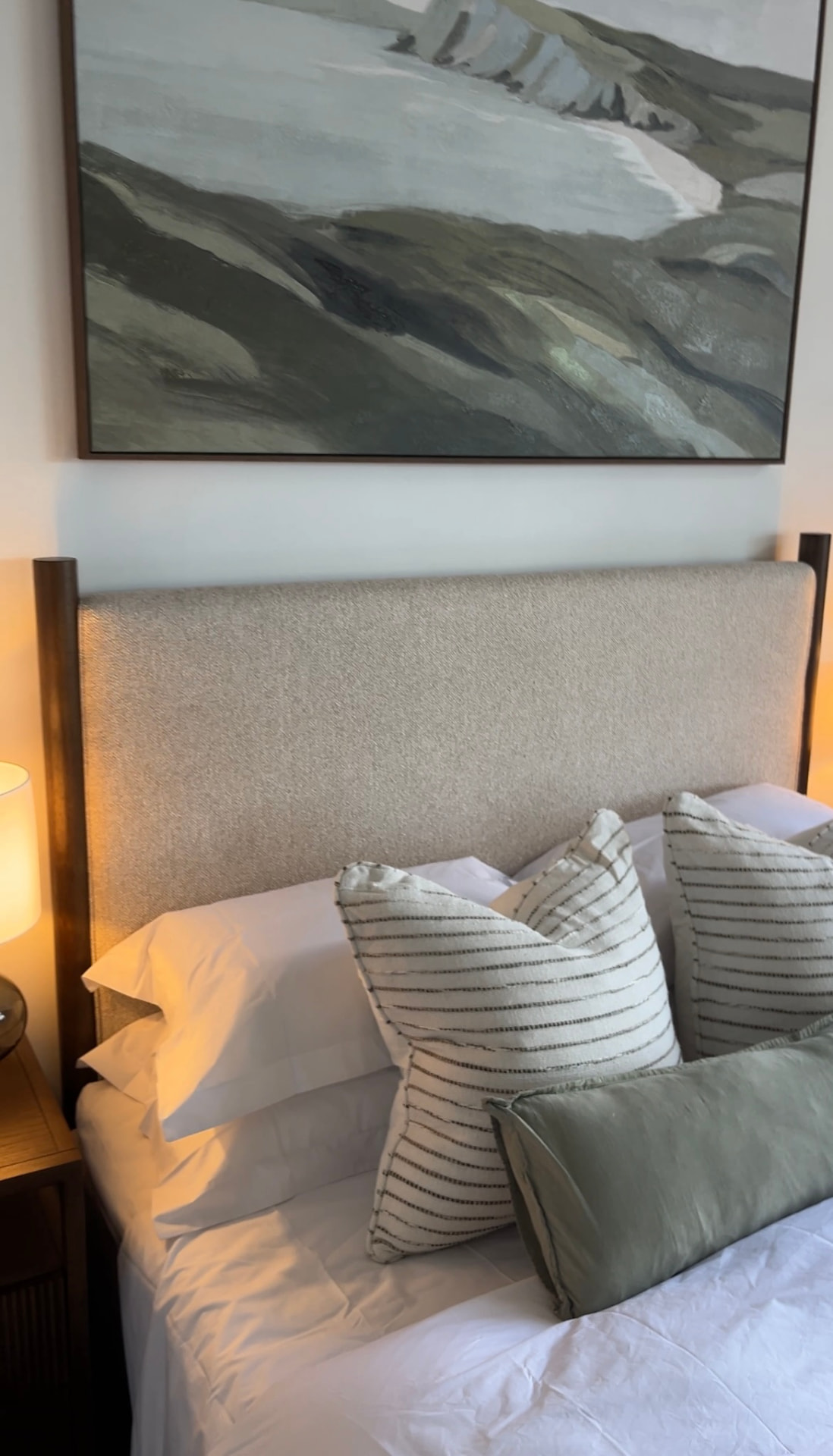 Close view of the framed landscape artwork above the linen headboard