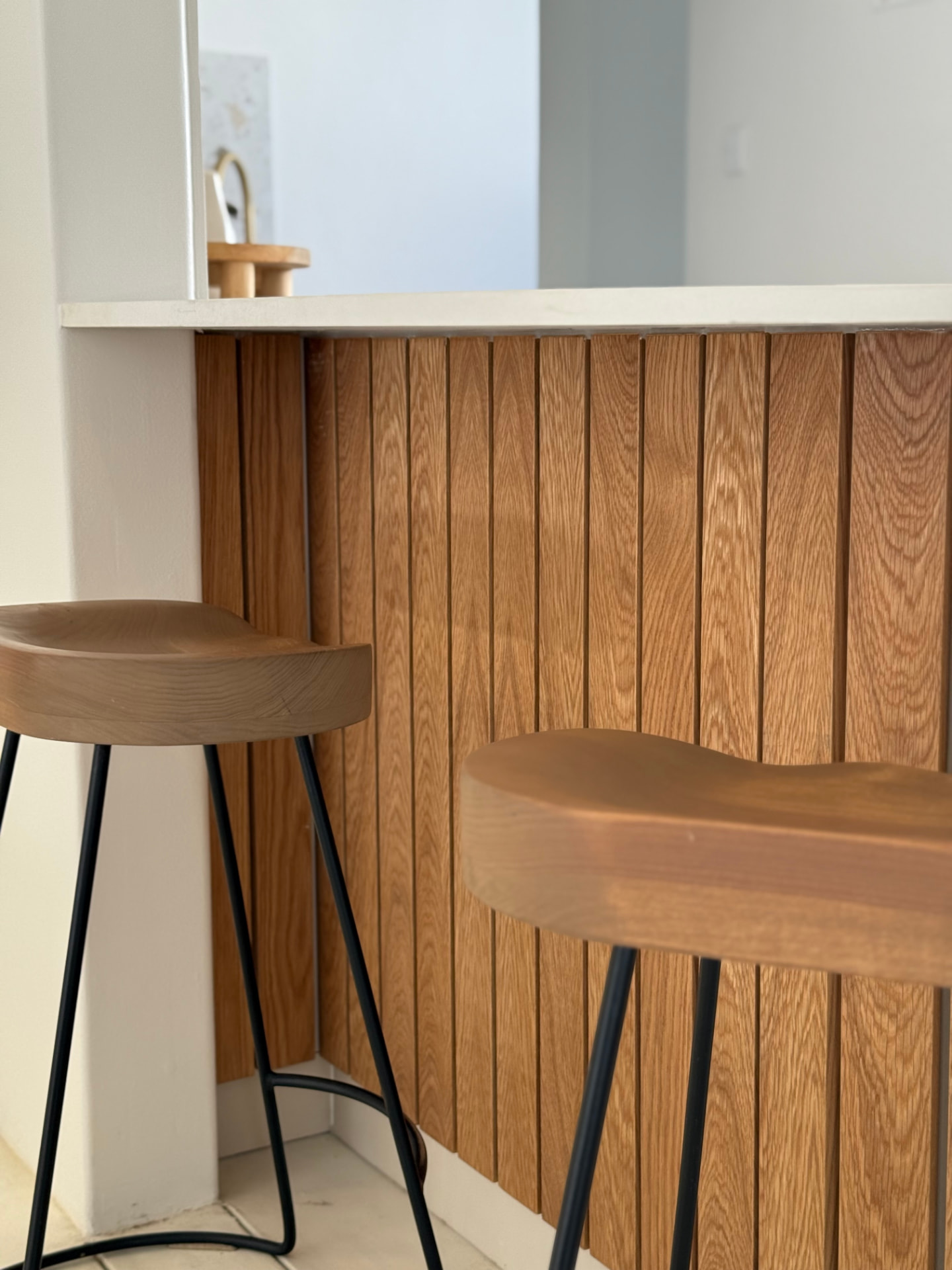 Fluted oak kitchen island with stone countertop and timber bar stools