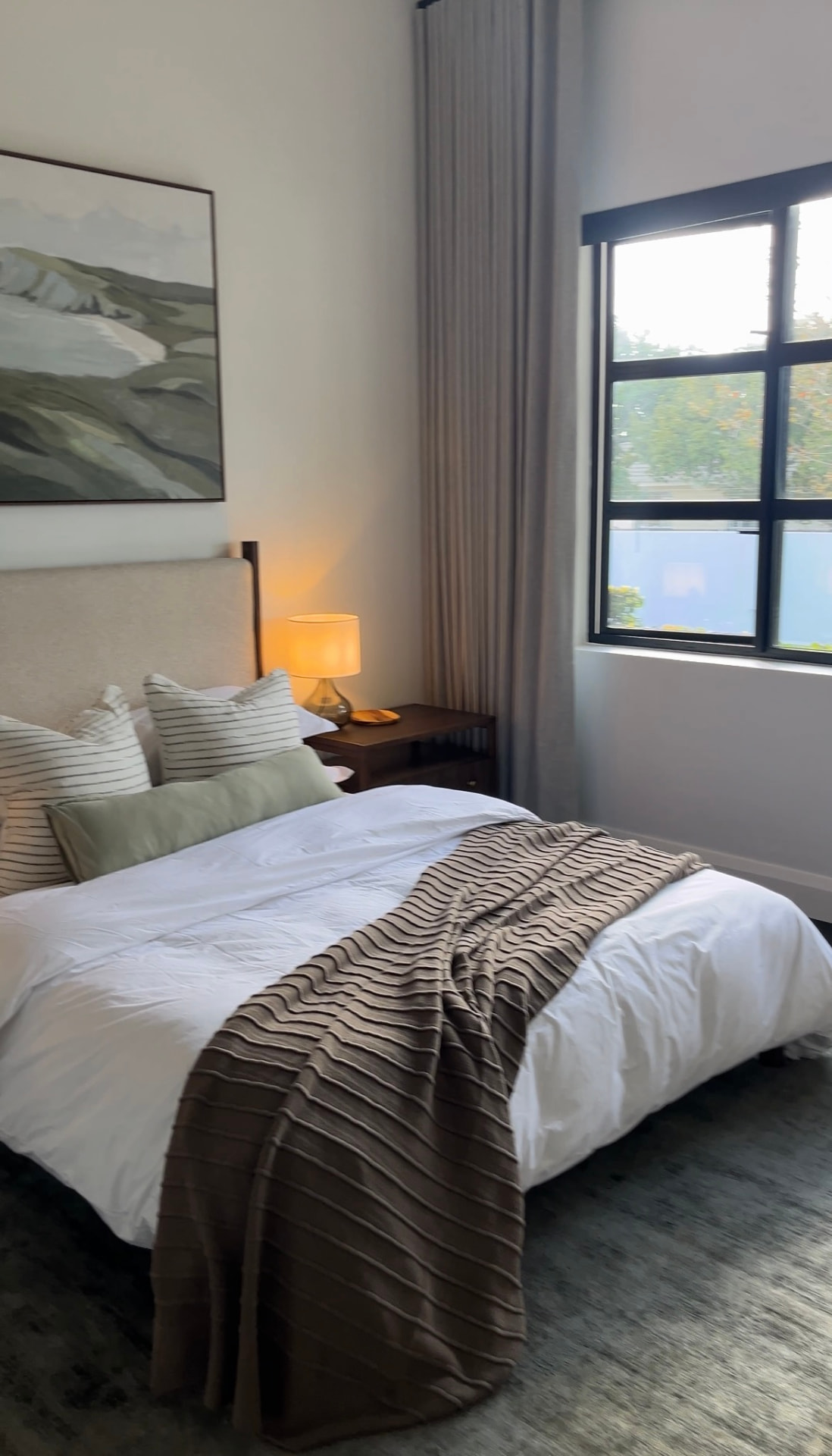 Guest bedroom with layered neutrals, warm timber and soft ambient lighting