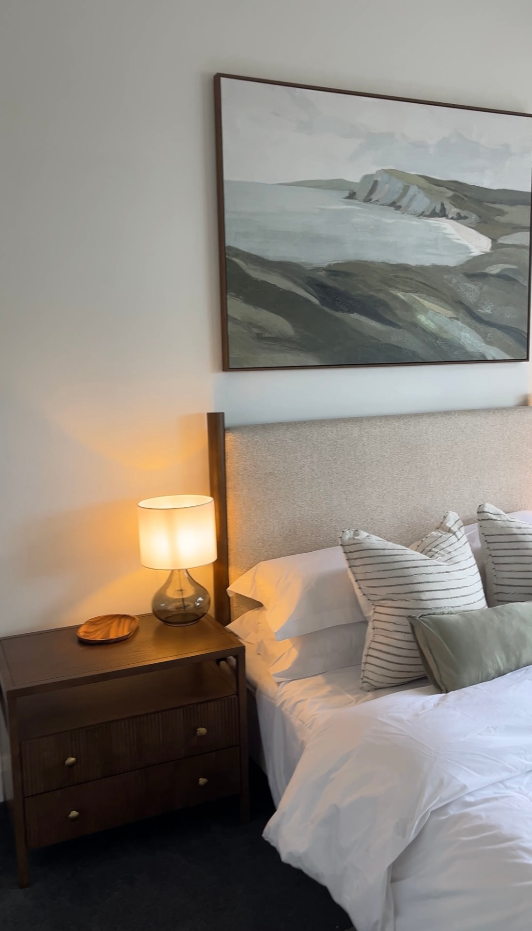 Fluted timber bedside chest with glass lamp and carved timber dish