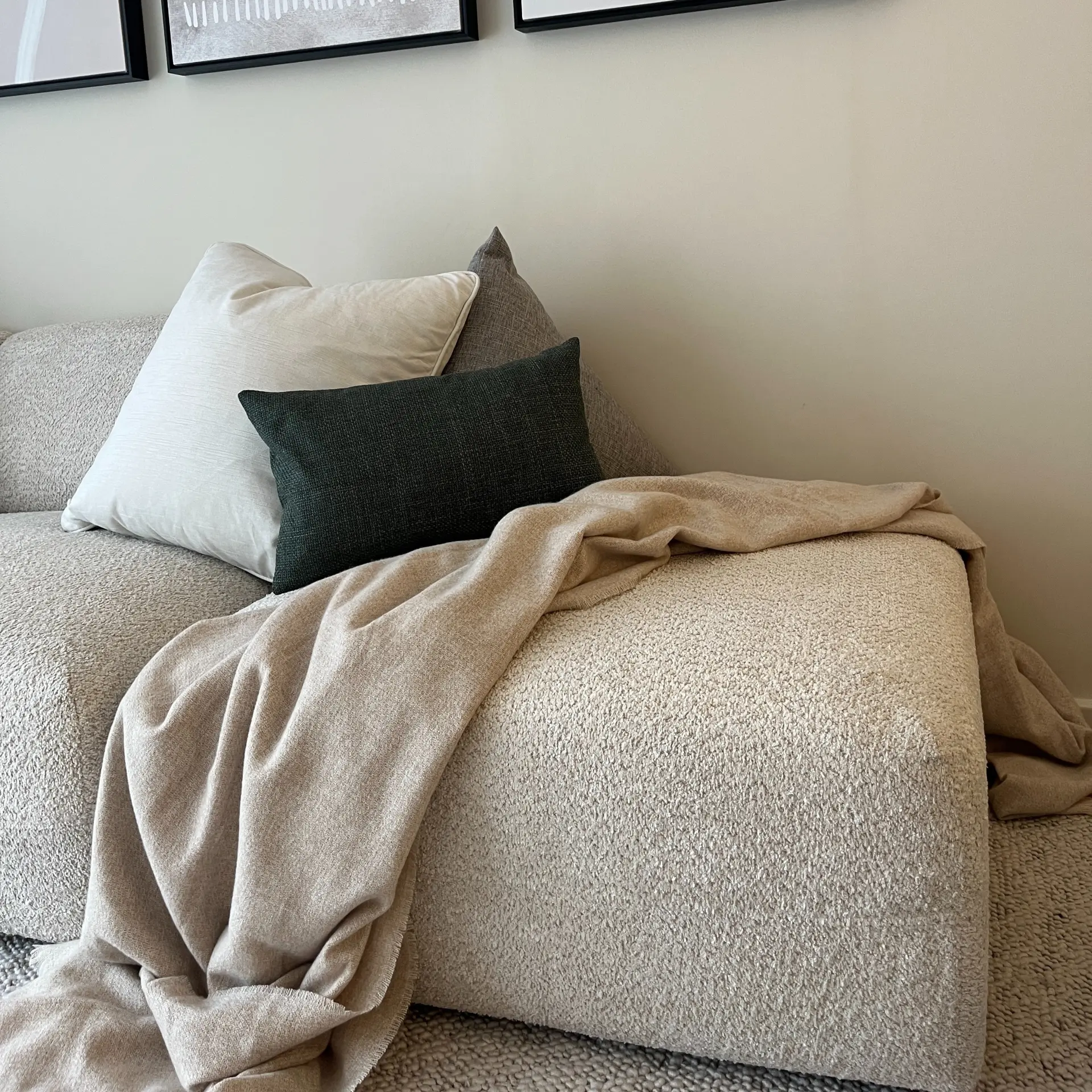 Bouclé sofa layered with linen cushions and a soft throw