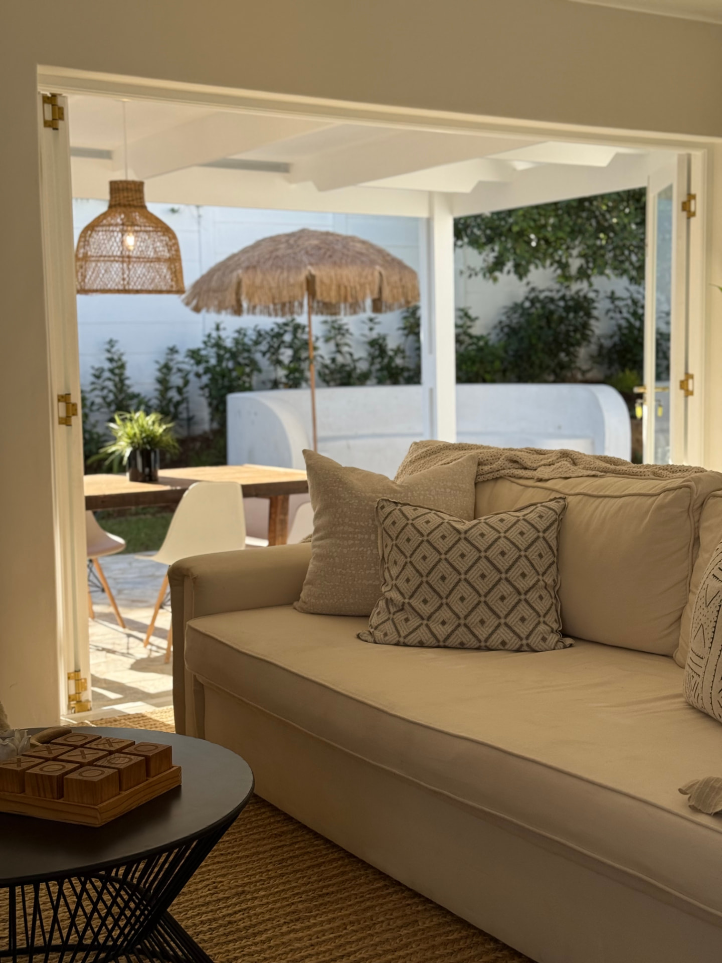 Living room opening onto a covered patio with rattan pendant and thatched umbrella