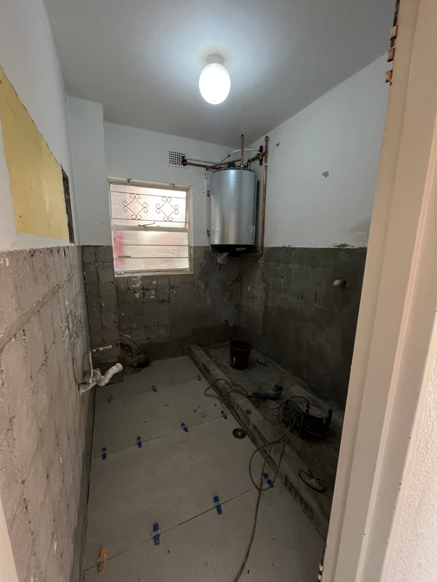 Bathroom stripped back to brick with new floor tiling being laid