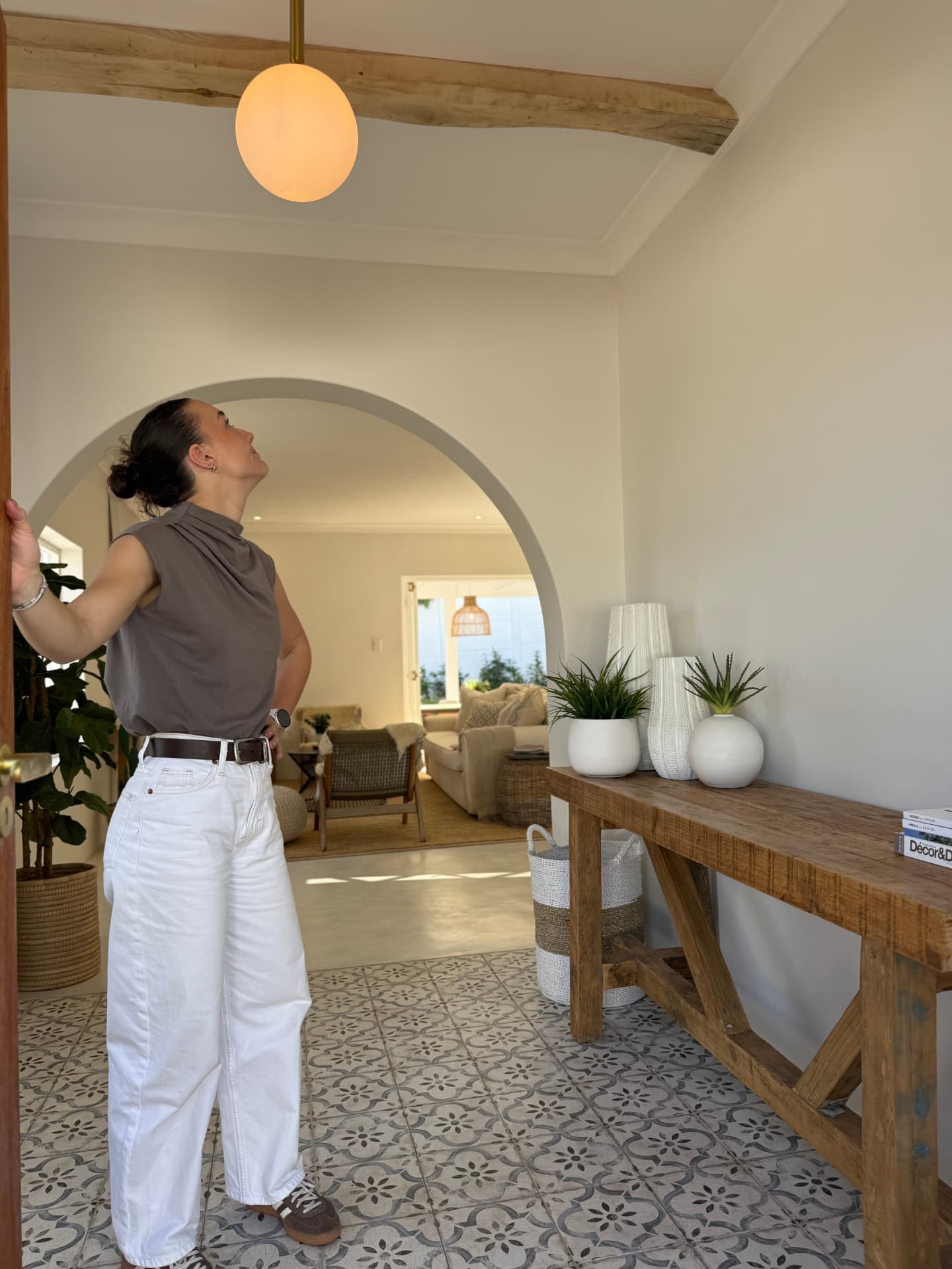 Arched entrance hall with patterned cement floor tiles, exposed timber beams and a rustic oak console
