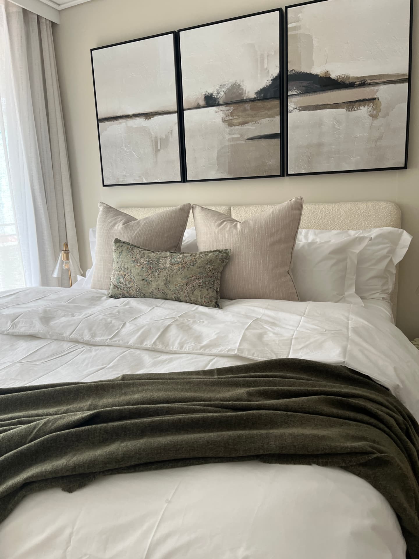 Main bedroom with bouclé headboard and abstract triptych artwork