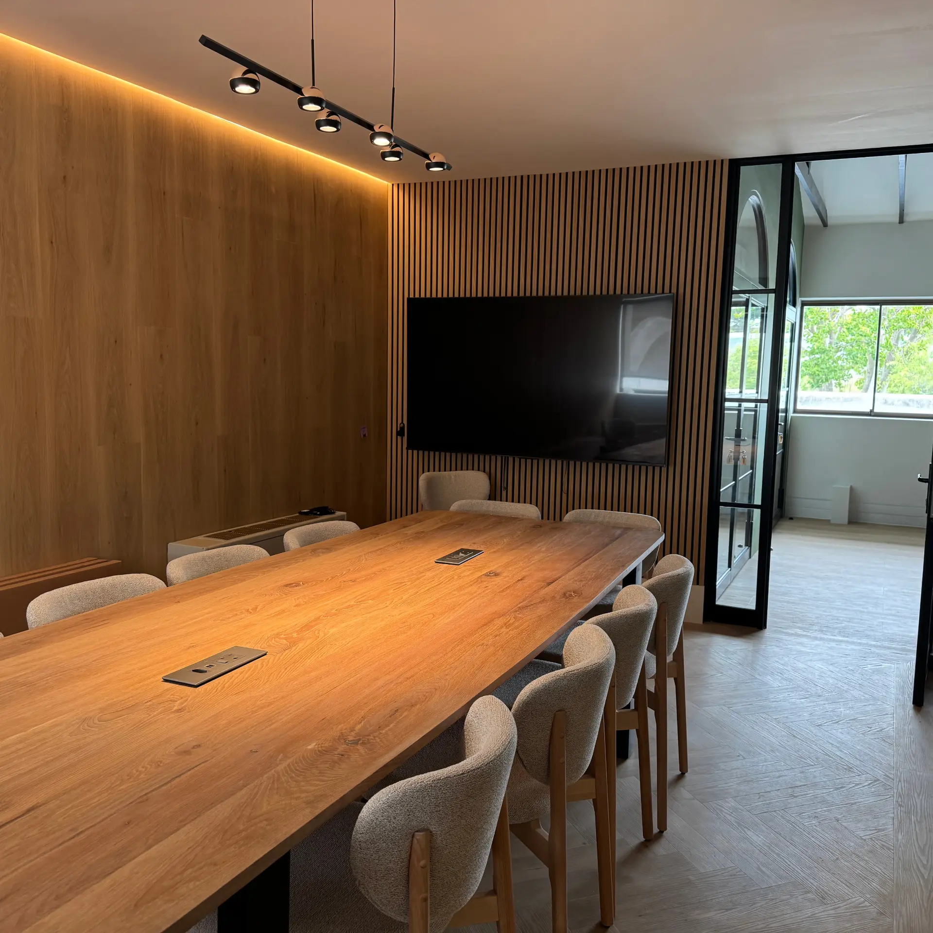 Boardroom with oak panelling, slatted acoustic wall and linear pendant