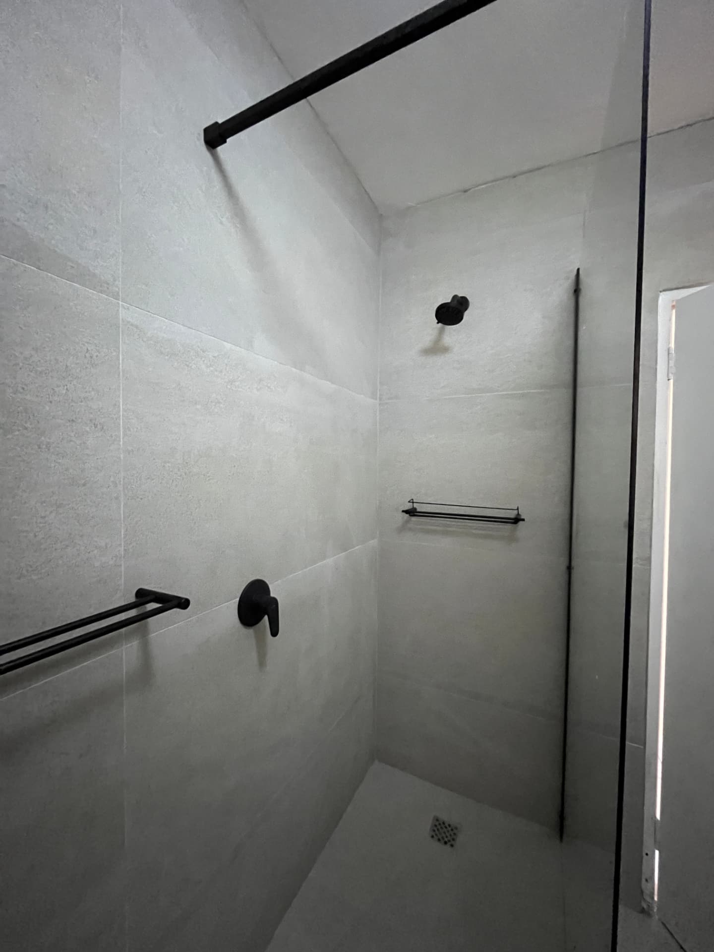 After: full shower enclosure with black grab rail, mixer and framed glass screen