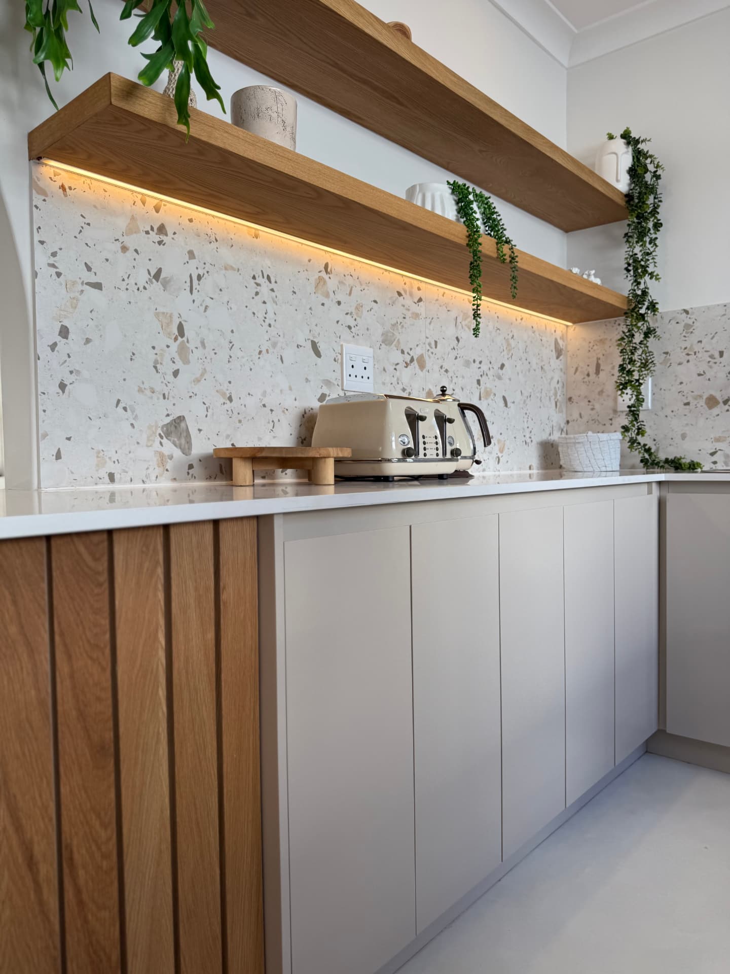 Kitchen with terrazzo splashback, lit floating oak shelves and fluted oak joinery