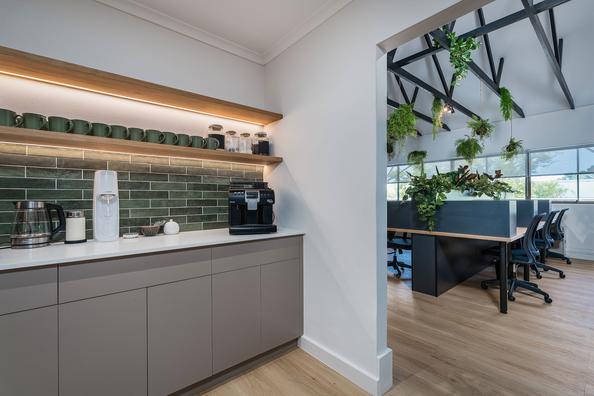 Kitchenette with green subway tile, oak shelving and integrated lighting