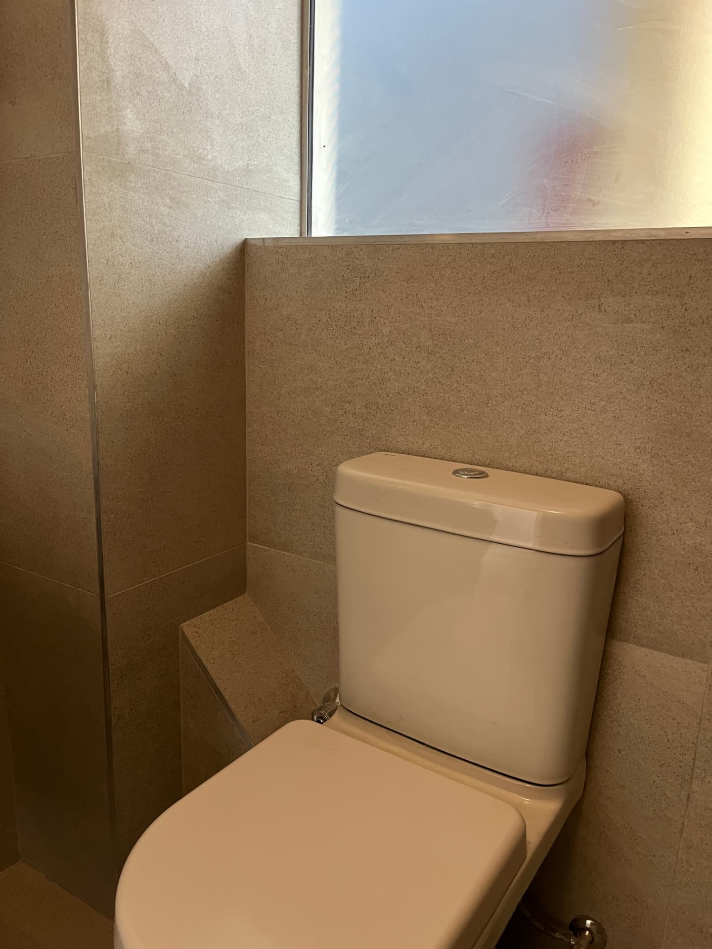 After: toilet niche detail in warm light with stone-look wall tiling