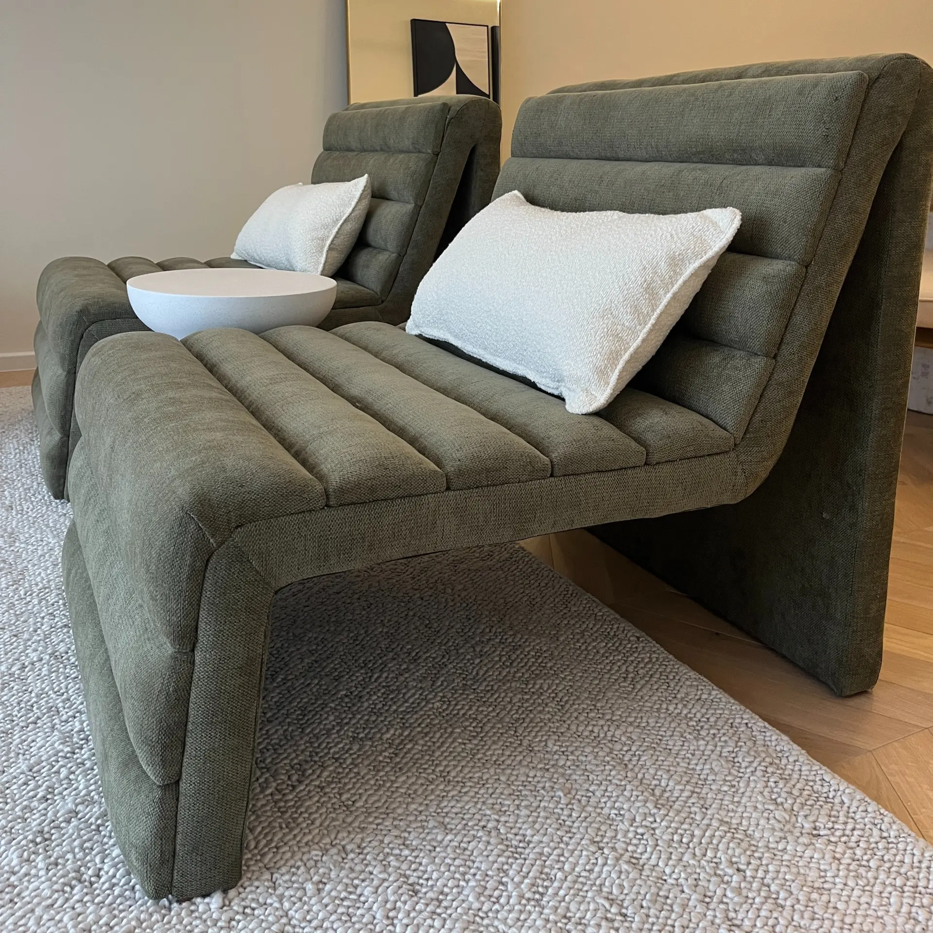 Olive green channel-tufted lounge chairs with bouclé cushions on a textured wool rug