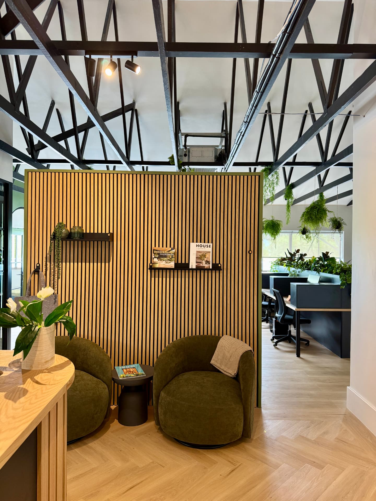 Waiting lounge with olive swivel chairs against a slatted timber screen